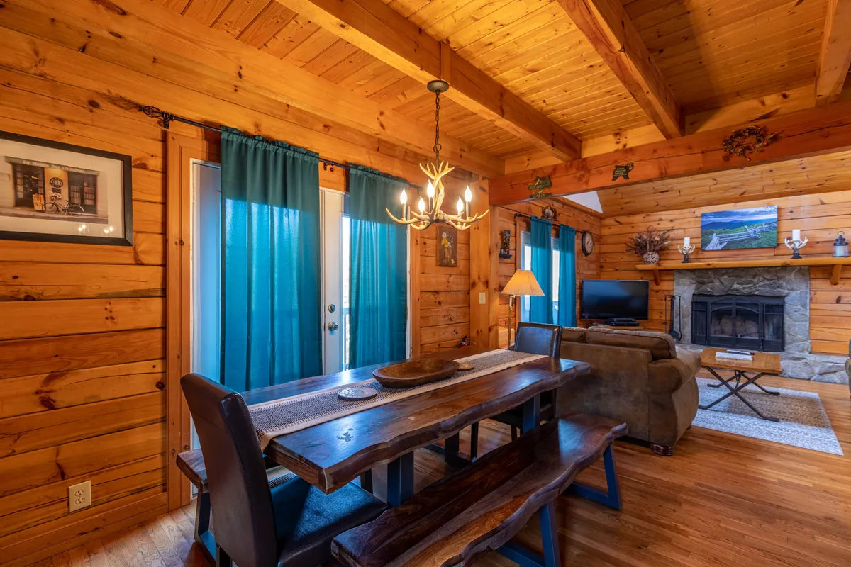 A warm and inviting dining and living space featuring a prominent fireplace, a large dining table for group meals or games, a plush couch, and a television—ideal for post-adventure relaxation and socializing.