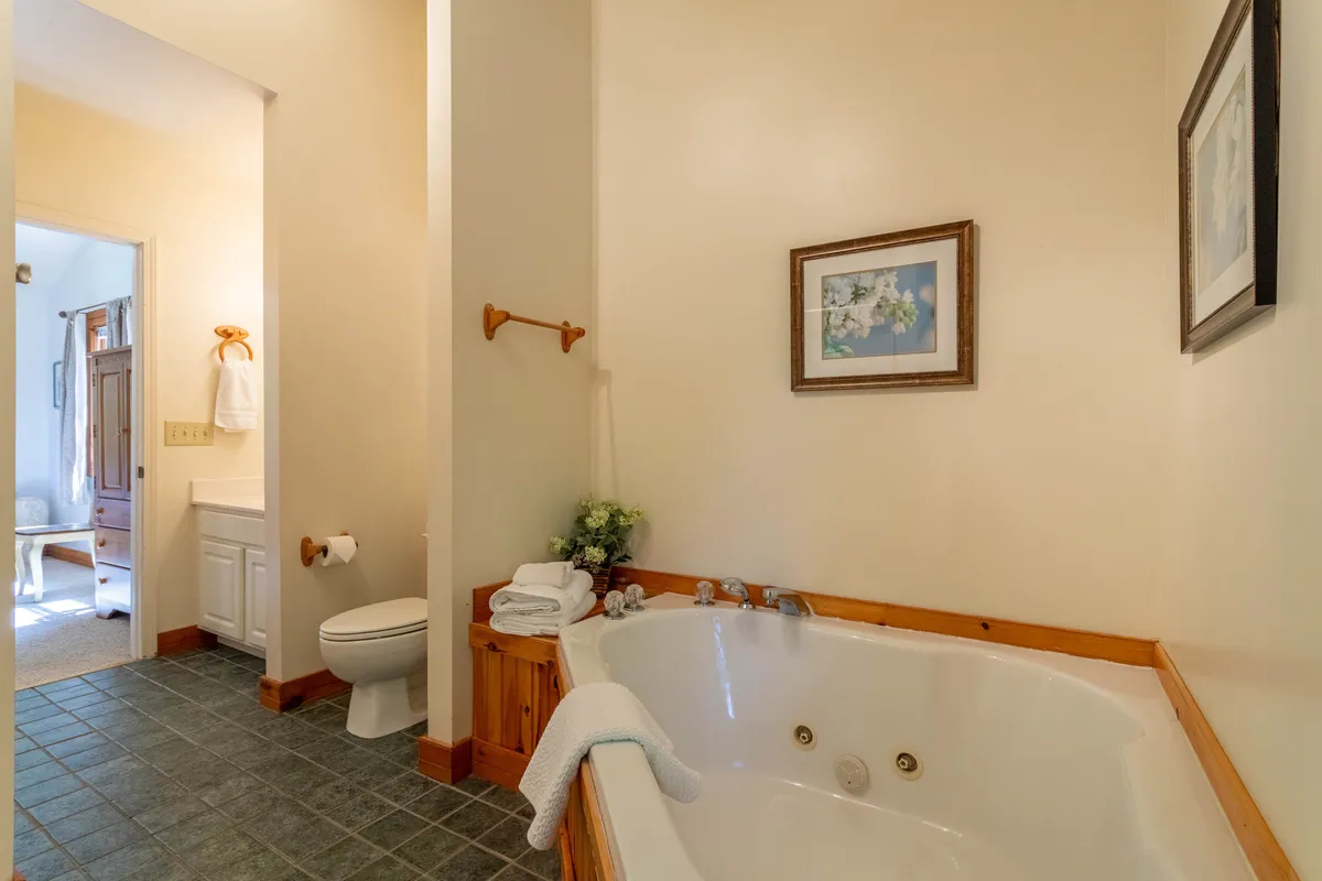 A tranquil bathroom centered on a spacious jacuzzi tub, complemented by framed artwork and neatly arranged towels. The serene setting suggests a spa-like experience ideal for relaxation and rejuvenation after active days.